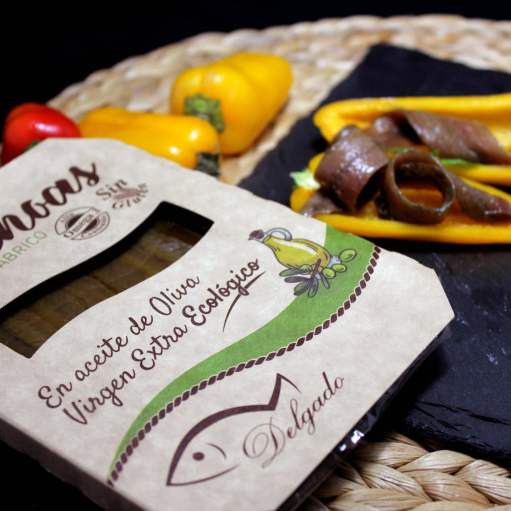 A tin can of Cantabrian Anchovies in Organic Extra Virgin Olive Oil, with the anchovies visible in the foreground on a piece of toast.