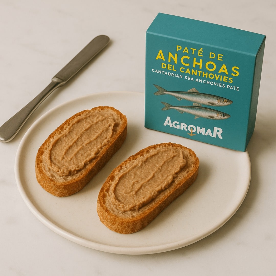 Two slices of bread with anchovy pate on a plate next to an Agromar box.