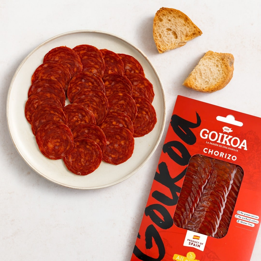 Goikoa chorizo slices on a plate with packaging and bread on a white background