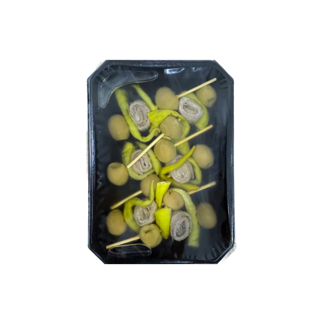 Packaged skewers of cantabrian anchovies, olives, and pickled green peppers on a black background.