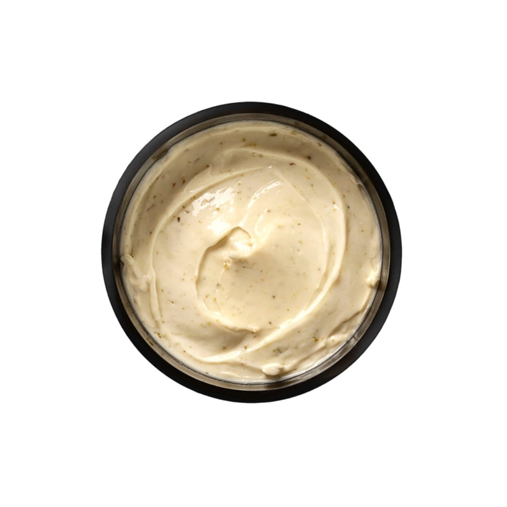Black container of creamy beige substance on a white background