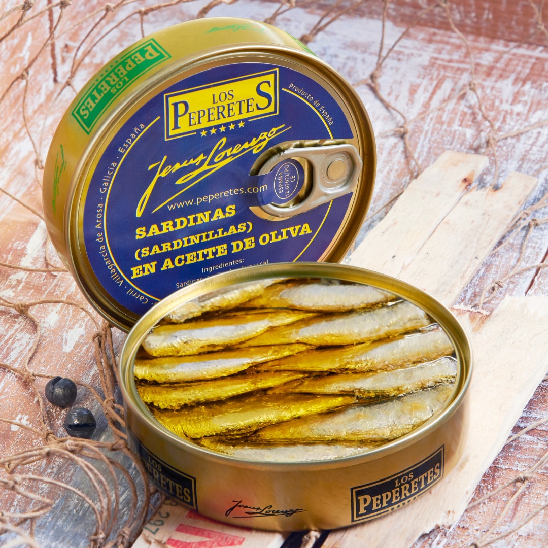 A tin can of Los Peperetes small sardines in olive oil, with the sardines visible inside the open can, placed on a wooden surface.