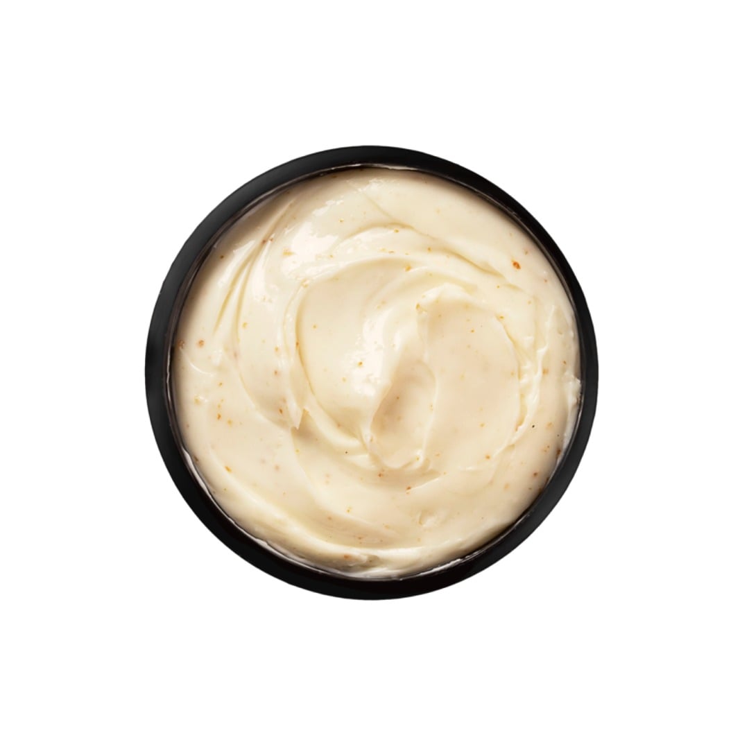 Black container filled with creamy white substance on a white background